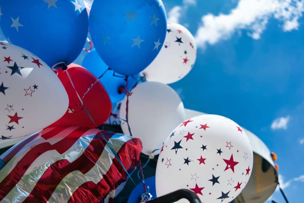 Photo of red, white and blue balloons with stars, and a red and white stripey ballon against a blue sky by Tom Dahm